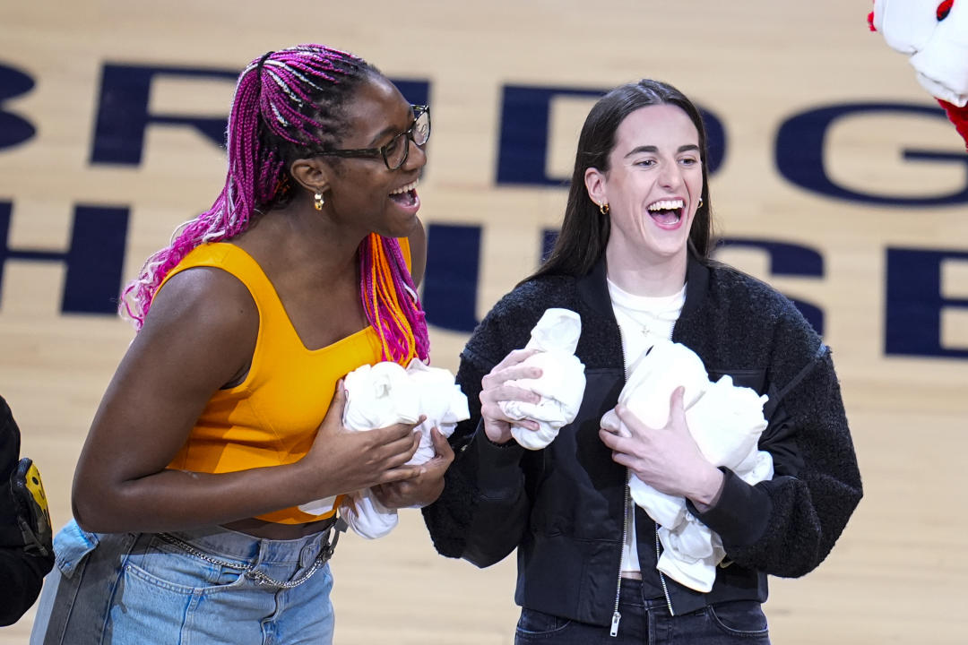Indiana Fever players Aliyah Boston, left, and Caitlin Clark throw jerseys to fans during a timeout during the first half between the Indiana Pacers and the Milwaukee Bucks in Game 2 of a first-round NBA basketball playoff series NBA, Friday, April 26.  2024, in Indianapolis.  (AP Photo/Michael Conroy)