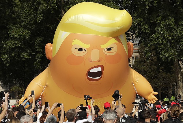 The huge inflatable shows the US president in a diaper and holding a mobile phone.