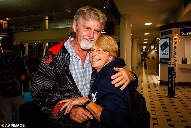 Rob Slade (pictured left) greets his partner Vicki Murray (right) after arriving from New Caledonia.