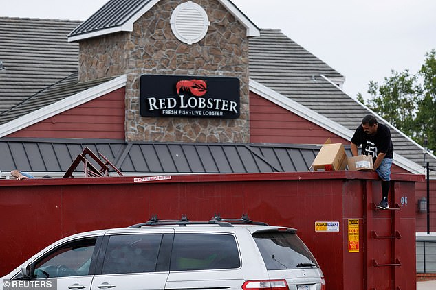 A man picks up items from a trash container in front of a closed Red Lobster restaurant whose entire contents are up for auction in San Diego, California, U.S., May 15, 2024.