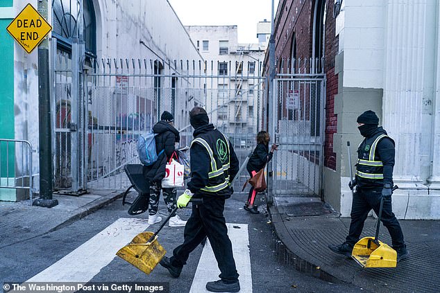 Early in the morning, a homeless man and woman quickly gather their belongings as Urban Alchemy crews begin their daily street cleanup in San Francisco's Tenderloin neighborhood.