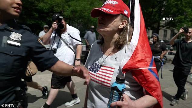 An apparently angry protester, while being held down by police, called the woman a 'fucking moron' and told her to 'burn in hell, you fucking liberal.'