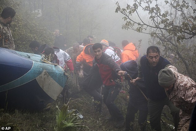 Rescuers at the site of a helicopter crash in a foggy, mountainous region of Iran