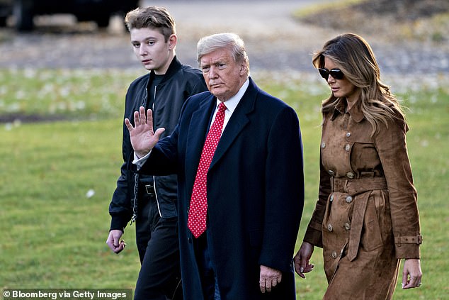 Then-President Donald Trump, center, waves as he walks with first lady Melania Trump, right, and their son Barron Trump on the South Lawn in November 2019.