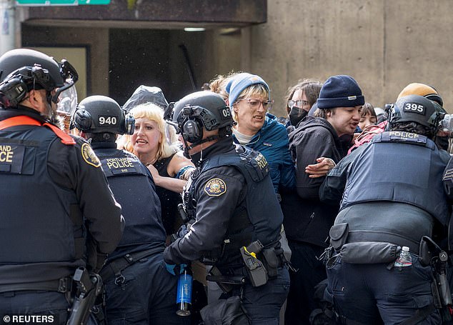 Police officers scuffle with protesters trying to block vehicles taking away the detained students, who had been occupying Portland State University's Millar Library.