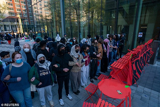 Pro-Palestinian students at New York University link arms as they occupy a seat at the university on April 26, 2024.