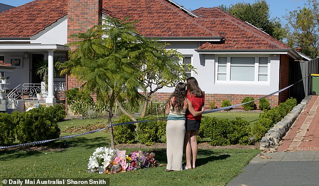 Two young people place a floral tribute at the crime scene