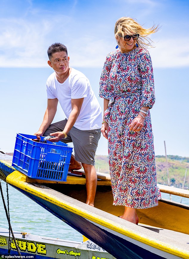 Queen Maxima wore her blonde hair down for a relaxed look and smiled as she stood on a small fishing boat.