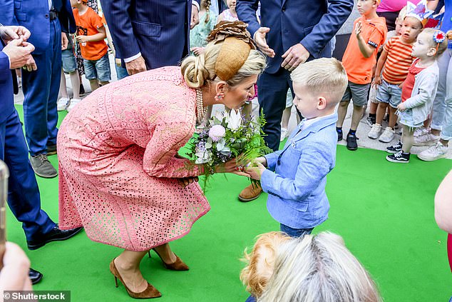 Máxima smiles as a young man gives her some flowers on her royal visit today.