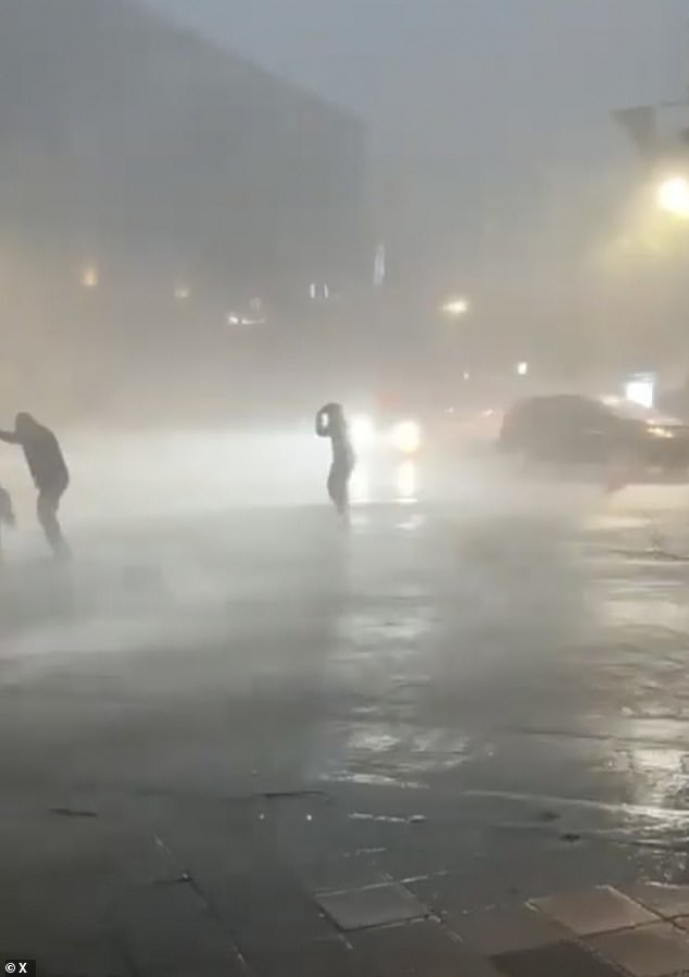 People are seen running for shelter as unprecedented rain falls on the city along with debris destroying homes and cars.