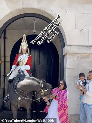 The horse turns its head before grabbing the woman's sari.