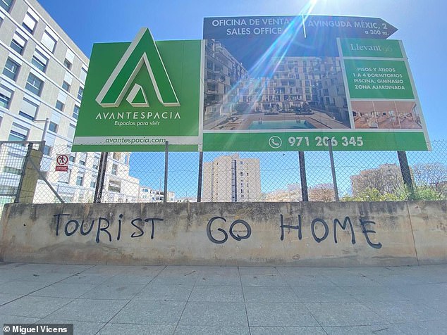 'Go Home Tourist' is scrawled in English on a wall beneath a property development sign in Nou Levante, Mallorca, a neighborhood that has seen a massive influx of foreign buyers in recent years.