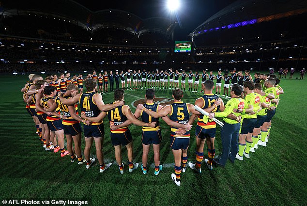 Adelaide and Port Adelaide players, along with match officials, observe a minute's silence for victims of gender-based violence in Australia before Thursday night's match.