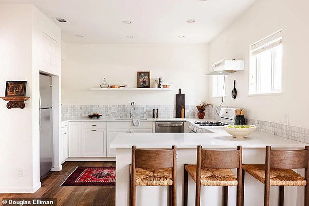 Further along the open plan home, there is a modern kitchen fitted with white cabinets, marble tiles and stainless steel finishes.