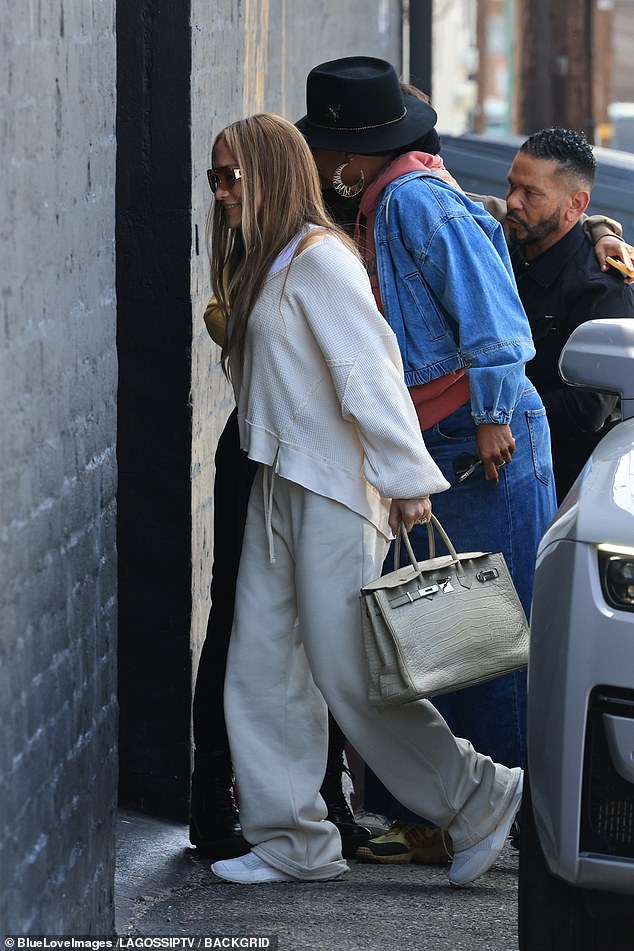 For the occasion, she wore an oversized white sweater over a matching tank top, sweatpants, sneakers, and oversized sunglasses over her light brown eyes.