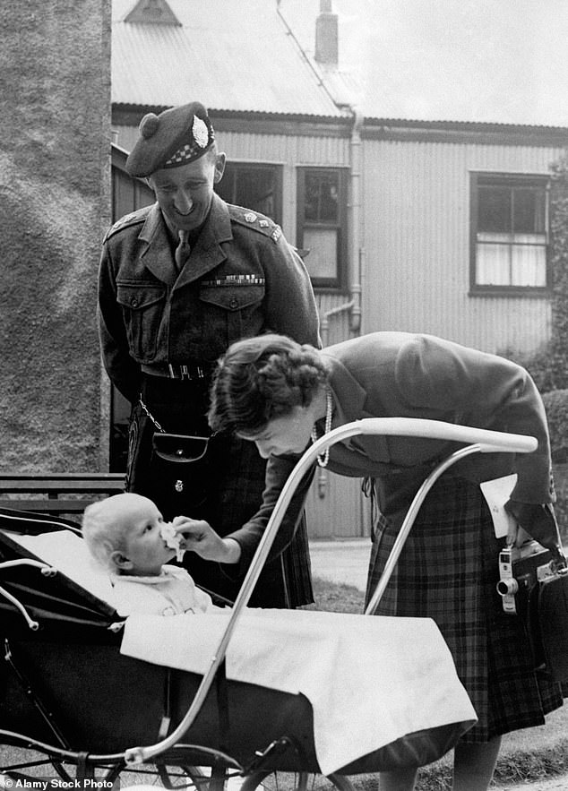 Princess Elizabeth bends down to wipe baby Princess Anne's nose before introducing her to Lieutenant Colonel Nielson, who commanded the 1st Argyll in Korea, during her summer holiday at Birkhall.