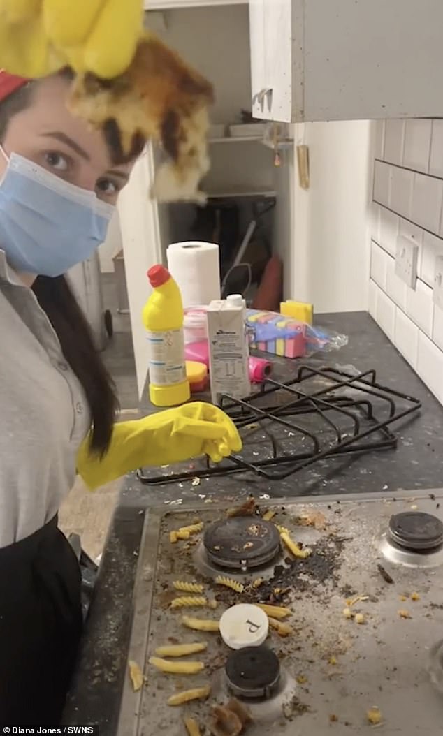 Wearing a mask and yellow rubber gloves, Diana holds up a nasty piece of trash she found while cleaning this dirty plate.