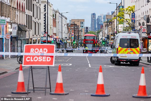 Pictured: Police guard the cordon at the scene in Dalston, east London.