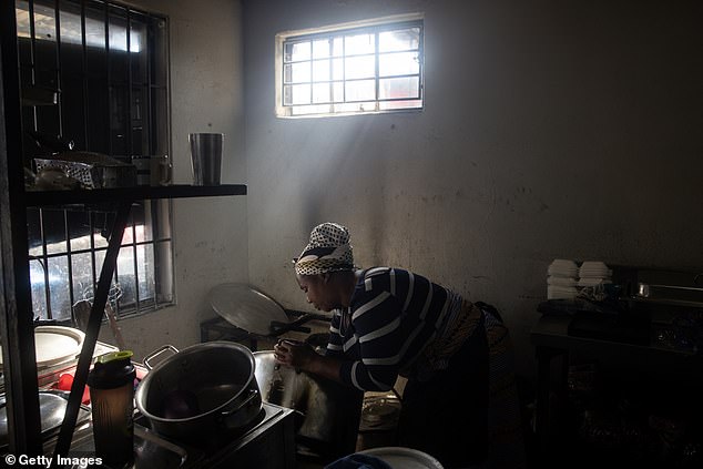 A woman cleans a pot in the kitchen of a restaurant in Alexandra township on May 31, 2024 in Johannesburg.