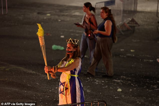 A woman dressed in an Israeli national flag holds a mock torch during a demonstration by relatives and supporters of Israelis held hostage by Palestinian Hamas militants.