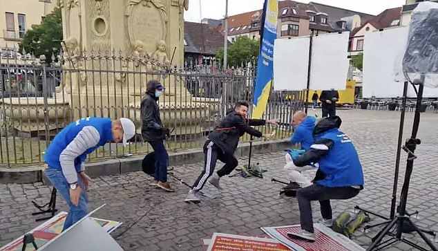 The rampage began when a man wearing a dark hooded jacket and tracksuit (seen center right) tackled a BPE member to the ground and began violently swinging a large sword at him.