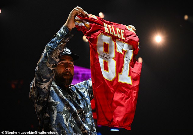 Kelce shows off his signed jersey, which was part of a $250,000 package on Saturday.