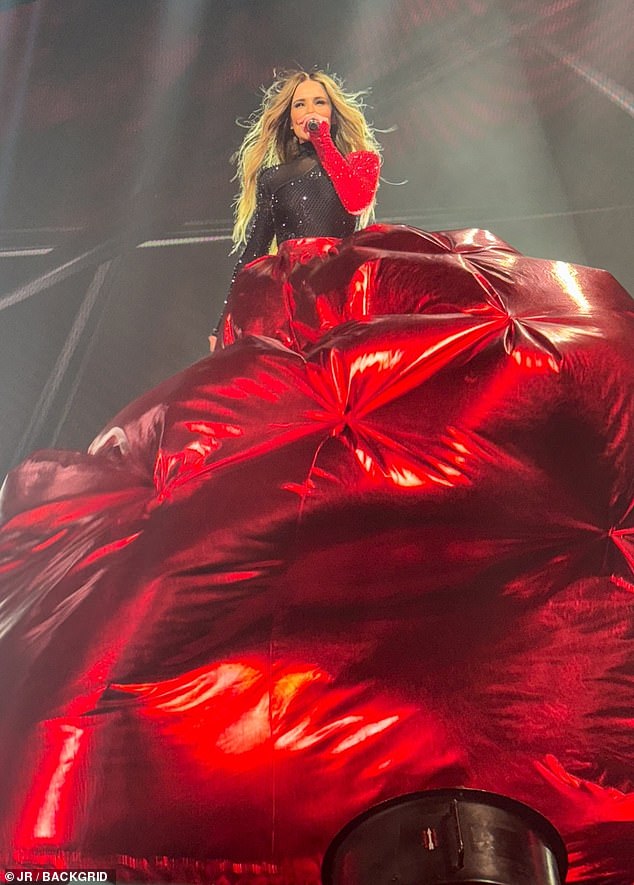 The show features a variety of flying stunts and here Cheryl is shown singing while leaning on a platform disguised by her huge red skirt.