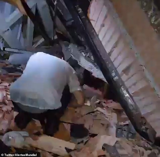 A wedding guest tries to help a person crawling under rubble after the ceiling collapsed at a wedding venue in Colombia on Saturday night. Two people were murdered