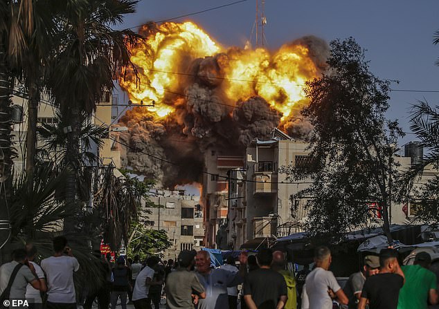 Palestinians watch in horror as an Israeli airstrike destroys a building in the Al Bureije refugee camp.