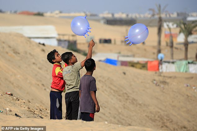 Displaced Palestinian children play with surgical rubber gloves in Rafah, southern Gaza Strip.