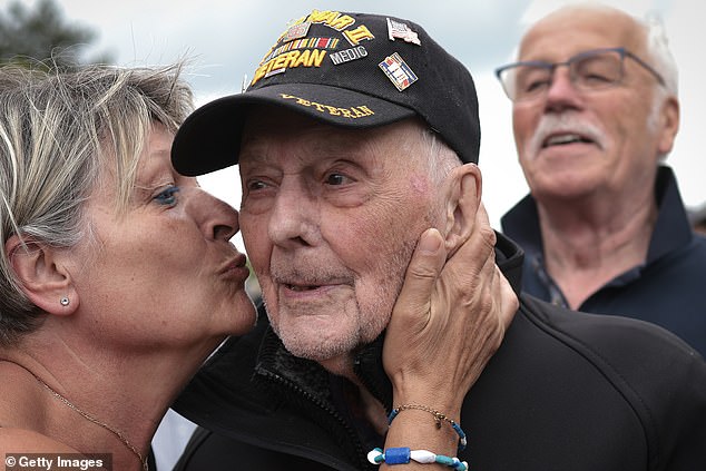 Gene Kleindl, a 102-year-old veteran of the historic day, receives a kiss while visiting the Normandy American Cemetery on Tuesday.