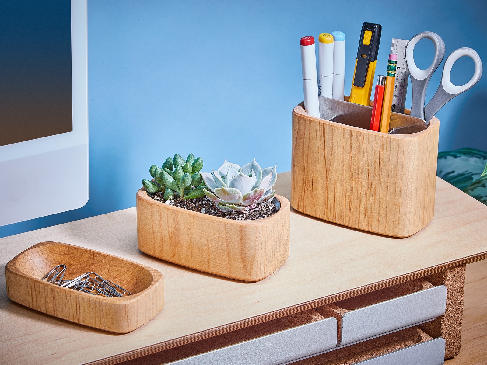 Simple two-tier wooden shelf with a computer monitor on top and 3 wooden containers containing clips, scissors and...