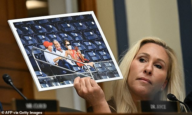 Rep. Marjorie Taylor Greene (R-Ga.) holds up a photo of Dr. Fauci with his mask placed under his chin at a baseball game during the pandemic during her questioning of the doctor at a House hearing Monday.