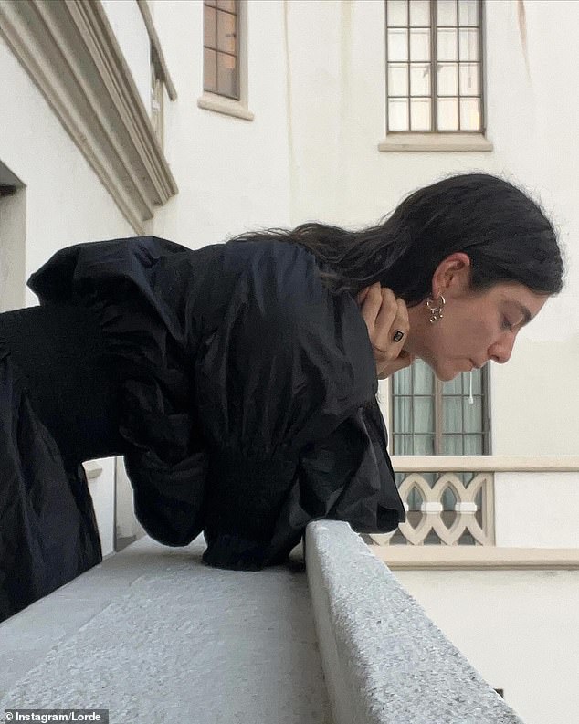 In the snapshots, the 27-year-old artist wore a long black dress while spitting off a balcony.