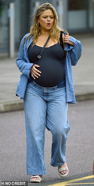 Emily looked radiant and glowing as she cradled her burgeoning baby bump in her chic denim ensemble.