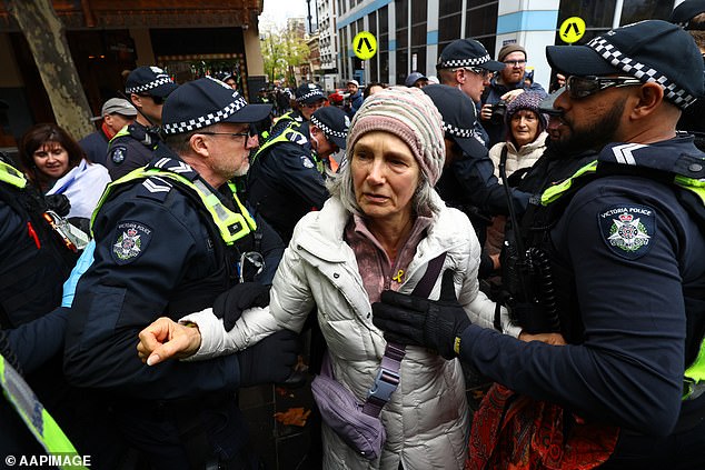 Police escort a woman during a 'Never Again' demonstration against anti-Semitism outside the Victorian Parliament in Melbourne, Sunday, May 19, 2024.