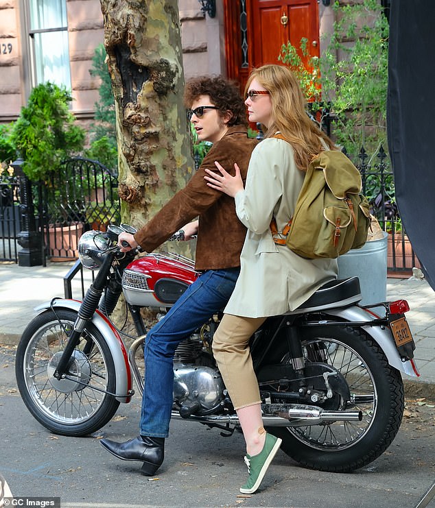 Fanning, who plays Suze Rotolo, Dylan's girlfriend from 1961 to 1964, wore a beige jacket, cropped khaki pants, green sneakers and a large backpack as she clutched Chalamet for support.