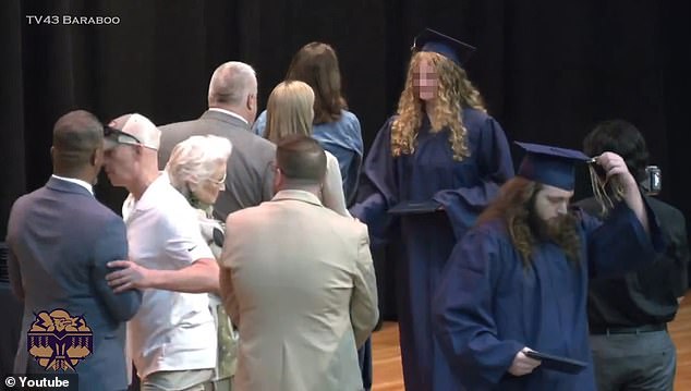 As his daughter made her way through a line of school officials, shaking their hands, Matt Eddy grabbed Superintendent Rainey Briggs by the arm and shoved him aside (far left).