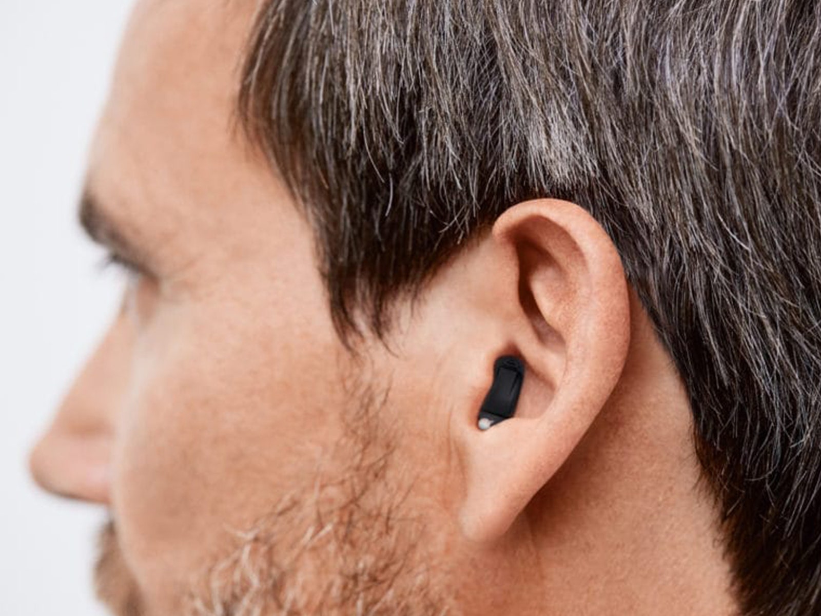 Close up view of a person's ear while wearing a black in-ear hearing aid