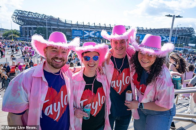 A group of Swifties wearing pink feather cowboy hats and Taylor t-shirts pose outside the stadium.