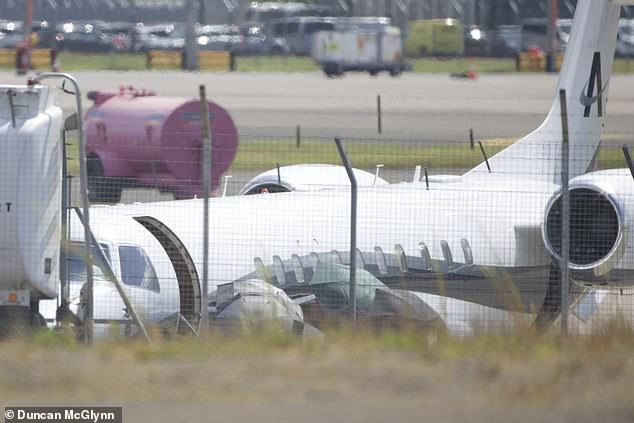 Taylor was hidden from view by black umbrellas as she exited the plane.