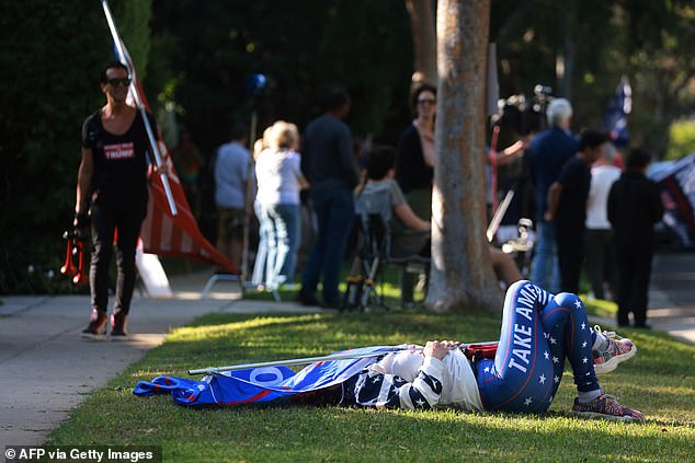 A supporter lies on the grass as former US president and 2024 Republican presidential candidate Donald Trump attends a fundraising dinner in Beverly Hills.