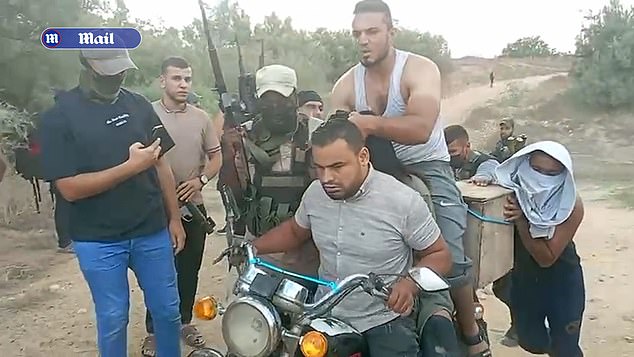 The chilling video shows Noa surrounded by at least ten armed terrorists (pictured), who can be heard taunting and shouting at her.