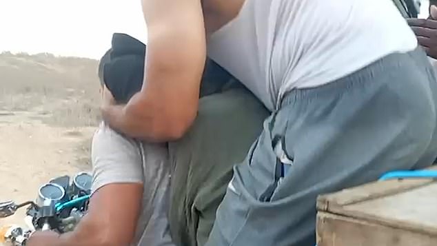 In images released in April, the woman can be heard crying as she is abused by a Palestinian fighter, who holds her head while placing a black bag over her face (pictured).