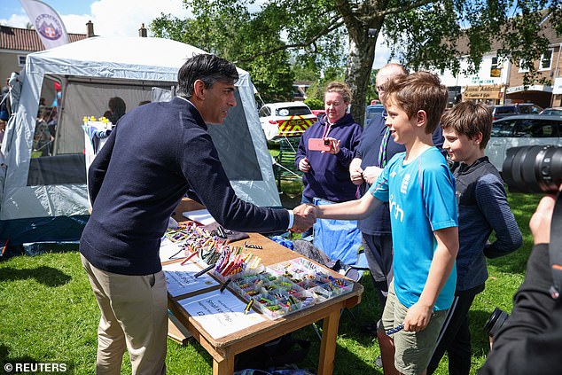 Sunak pictured shaking hands with a child today at a Conservative general election campaign event in Great Ayton