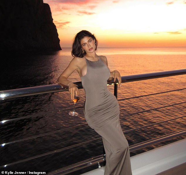 Kylie wore a tan ensemble that clung to her body for another night and stopped to take a photo with the colorful sunset in the background.