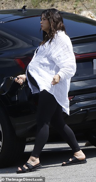 Dewan cut a casual figure in an oversized white button-down shirt and a black tank top underneath.