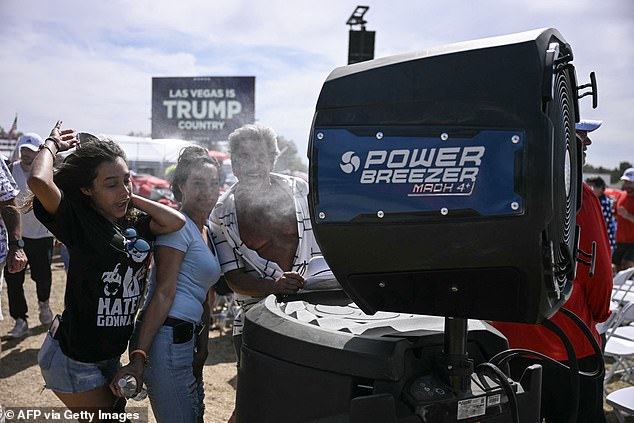 A woman's hat falls off while standing next to a cooling station outside Trump's rally in Las Vegas.