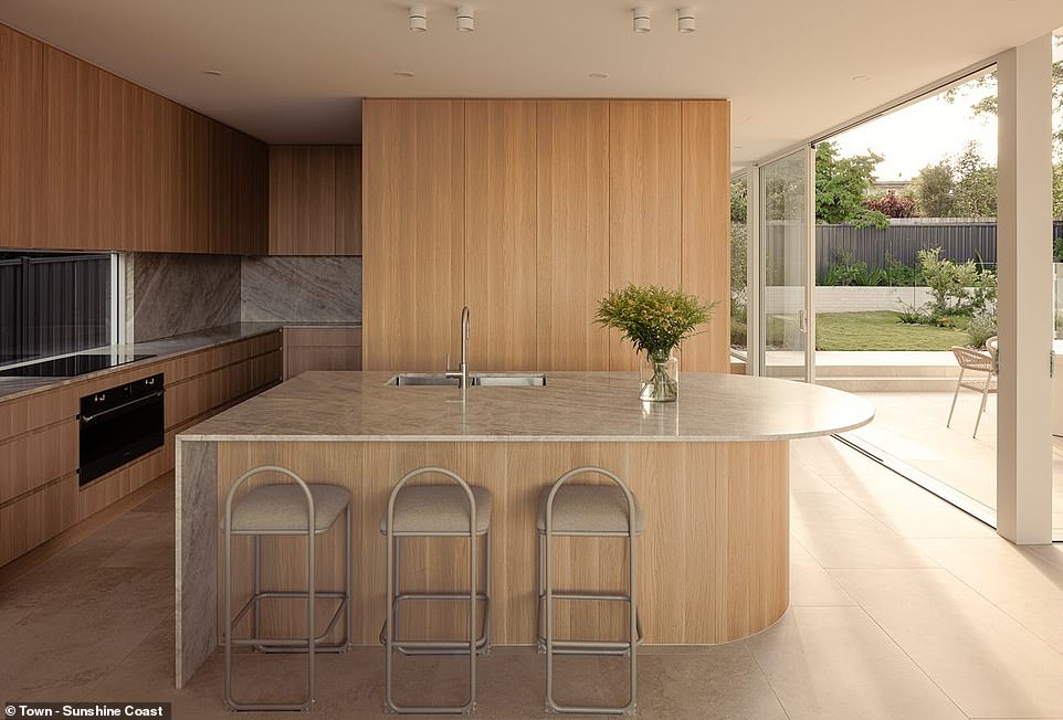 The elegant kitchen features a curved marble bench with island, a glass splashback and storage hidden behind smooth wooden doors and a study nook hidden behind the pantry.