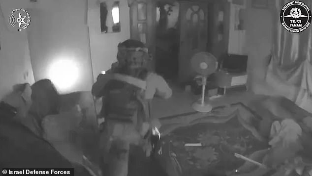 In the video, forces break into the apartment, searching for targets before breaking into a bedroom where three men can be seen crouching.